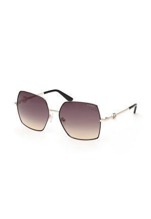 Gafas de sol de forma cuadrada con lentes marrones con degradado, montura metálica delgada dorada, extremos de las patillas en negro y logo de Guess en la lente y las patillas.