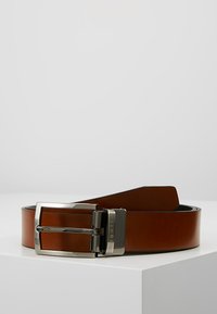 Ceinture en cuir brun avec une boucle en métal argenté. Texture lisse, design plat et fonction de longueur ajustable.
