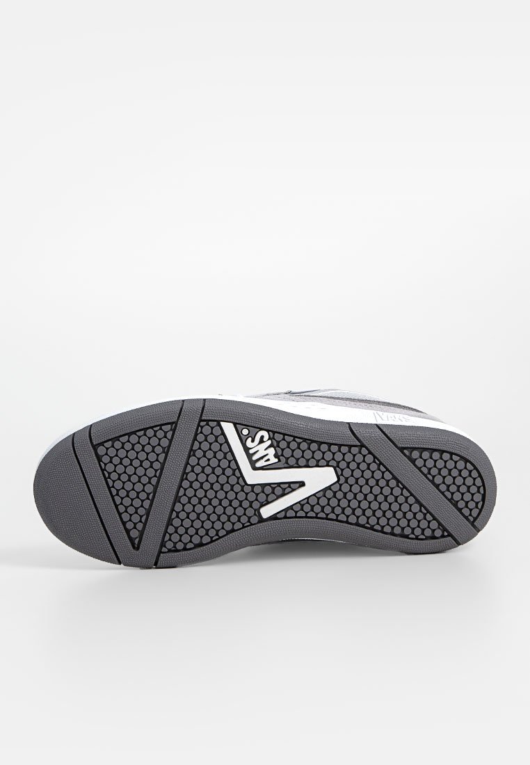 Sole di una sneaker Vans che mostra un motivo a nido d'ape nero con il logo Vans bianco e bordi in gomma grigia su una superficie bianca.