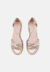 Metallic Sandalen mit silbernen, goldenen und roségoldenen Kreuzriemen. Knöchelriemen mit Schnalle, gepolsterte Innensohle und geflochtenes Sohlenmuster.