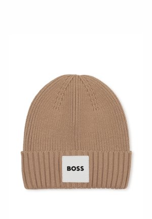 Lichtbruine geribbelde gebreide muts met omgeslagen rand en een wit rechthoekig label met de tekst "BOSS" in het midden aan de voorkant.