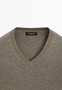 Brązowy dziergany sweter z dekoltem w serek, z prążkowanym kołnierzem i metką Massimo Dutti wewnątrz kołnierza.
