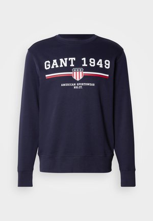 Sudadera de color azul marino hecha de algodón, con cuello redondo. Logo impreso "GANT 1949" con escudo y rayas en rojo y blanco.
