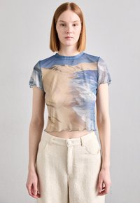 Kortsleved crop top med trykk av strandmotiv i blått og beige, med en bølgekant og myk, gjennomsiktig tekstur.