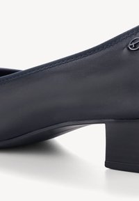 Décolleté in pelle blu navy con punta rotonda, tacco basso a blocco e dettagli di cucitura discreti. Presenta un piccolo logo sul lato.