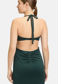 Grünes Halterkleid mit gerafftem Rücken, verziert mit einem Paillettenbesatz. Der Stoff wirkt glatt mit einem leichten Glanz.