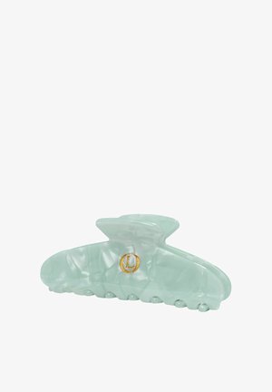 Pinza para el cabello de plástico marmoleado verde claro con un pequeño emblema circular dorado en el lateral.