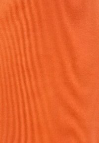 Tissu côtelé dans une teinte orange vive, avec des lignes verticales. Texture lisse, léger, convient à divers vêtements.