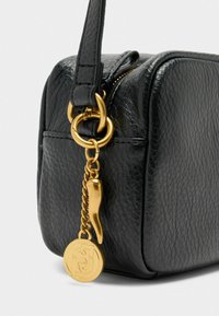 Borsa in pelle nera con forma quadrata, dotata di hardware dorato, una catena decorativa dorata e un ciondolo con design di peperoncino.