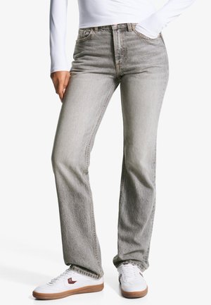 Light grey denim jeans with a straight leg design, five pockets, and subtle fading. Paired with white sneakers for a casual look.