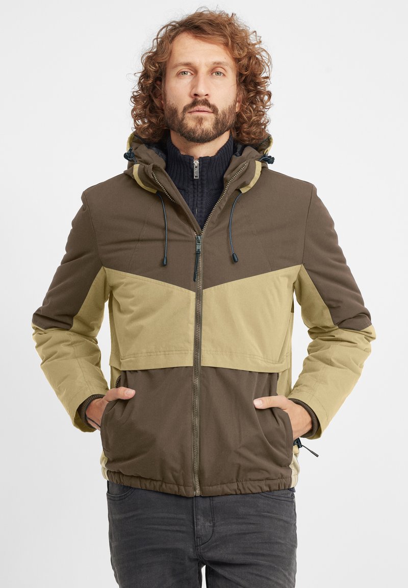 Color-blocked jacket in olive green and brown, featuring a hood, front pockets, and a zip closure. Fabric appears textured and durable.