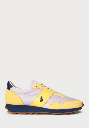 Sapatilhas com atacadores em amarelo, lavanda e azul-marinho, com materiais de malha e camurça, apresentando uma sola texturizada e um detalhe com o logo.