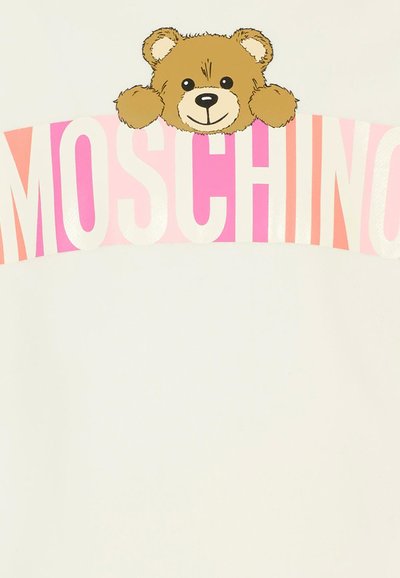 T-shirt bianco con una grafica di un orso di peluche marrone e un volto sorridente, sopra il nome del marchio "Moschino" in lettere cubitali rosa e rosse.