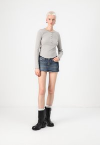Grå langermet topp med knappdetaljer, kombinert med en blå denim mini-skjørt. Svart ankelstøvler med klumpete hæl og sølvfarget utstyr.