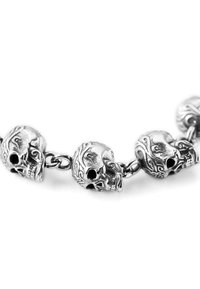 Silver skull bracelet featuring intricately detailed skull charms, chain links, with a metallic finish and textured patterns on the skulls.