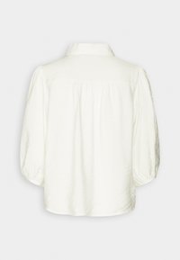 White blouse with a collared neckline, long puffed sleeves, and a textured, slightly shiny fabric. Features gathered detailing at the back.
