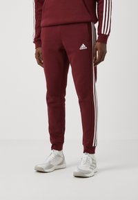 adidas Sportswear ESSENTIALS TAPERED CUFF 3-STRIPES  - Treniņtērpa apakšdaļas - shadow red