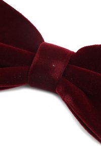 Bordeaux fluwelen strik met een zachte textuur, voorzien van een centrale knoop en scherp toelopende uiteinden, tegen een witte achtergrond.