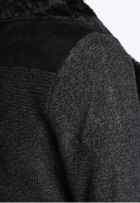 Black and grey textured coat featuring a plush neck area, smooth black shoulder details, and a tailored fit, highlighting fabric contrast.