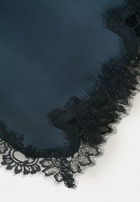 Tissu bleu foncé avec une large bordure en dentelle noire présentant des motifs floraux et en filet le long du bord.
