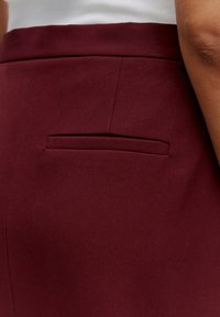 Bordeaux rok met een subtiele diagonale textuur, een kleine, platte achterzak en een getailleerd silhouet.