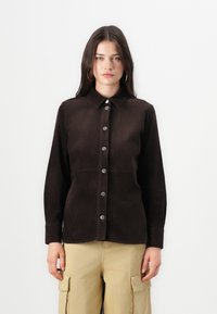 Brown corduroy shirt with a collar, front button closure, and long sleeves. Features vertical ribbed texture and contrasting metal buttons.