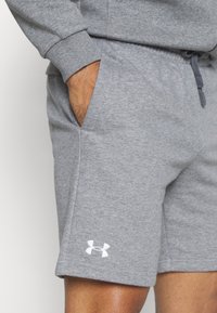 Graue Sweat-Shorts aus Baumwollmischung, mit seitlichen Taschen, elastischem Bund mit Kordelzug und einem weißen Logo am unteren Saum.