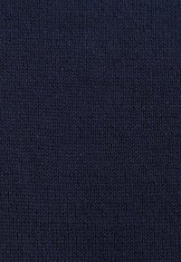 Tissu tricoté bleu marine avec un motif de points serrés et réguliers et de légères variations de texture sur toute la surface du textile.