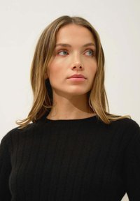 Czarny sweter prążkowany z okrągłym dekoltem, charakteryzujący się miękką teksturą i dopasowanym krojem, prezentowany na neutralnym tle.