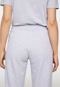 Lichtgrijze sportbroek met een elastische tailleband, met een gladde, soepele textuur en een relaxte pasvorm. Van achteraf gezien.