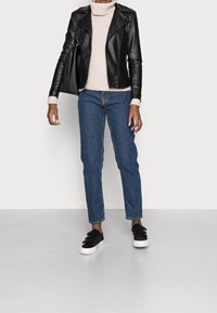 Svart läderbikerjacka, beige polotröja, blå raka jeans och svarta sneakers med vita sulor. Avslappnad klädsel.