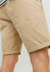Beżowe bawełniane szorty z podwiniętymi mankietami i bocznymi kieszeniami, o gładkiej fakturze i prostym kroju, idealne na co dzień.