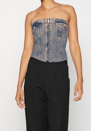 Top corsetto in denim con zip frontale, forma strutturata e senza spalline. Lavaggio blu chiaro con due tasche frontali e dettagli di cucitura a contrasto.