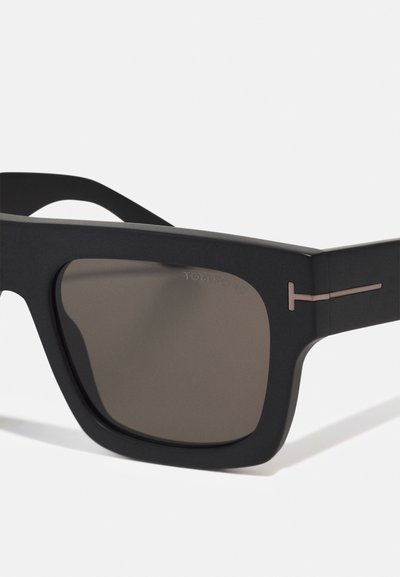 Lunettes de soleil noires avec une finition mate, de forme rectangulaire, verres marron et une subtile finition en métal. "TOM FORD" gravé sur la monture.
