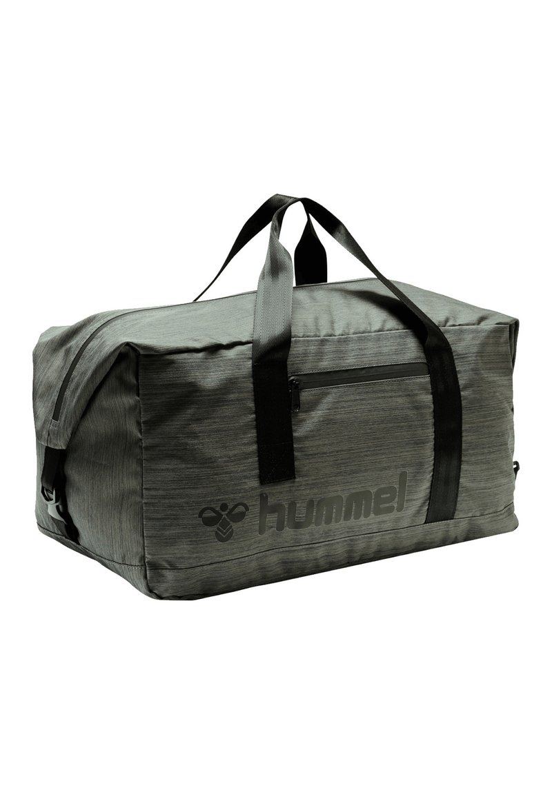Sac de sport gris avec tissu texturé, sangle noire, poche zippée à l'avant et grand logo "hummel" sur le côté. Forme rectangulaire.