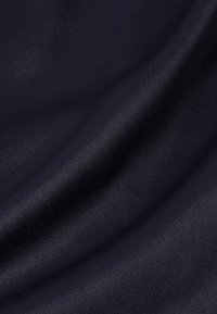 Gładka ciemnoniebieska tkanina z delikatnymi skośnymi fałdami i lekko teksturowaną powierzchnią.