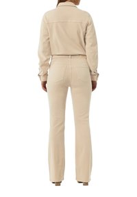 Chemise en denim beige et pantalon évasé, présentant une texture lisse et une silhouette ajustée avec deux poches arrière. Détails de design minimalistes.