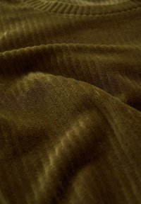 Tessuto verde oliva textured con motivo a coste, caratterizzato da una consistenza morbida e vellutata e da sottili variazioni di ombreggiatura.