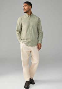Lichtgroen button-up overhemd gemaakt van zachte stof, gecombineerd met crèmekleurige broeken en donkere schoenen. Beschikt over een borstzak en een collared ontwerp.