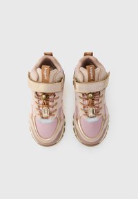 Zapatillas deportivas rosa claro con acentos beige, que cuentan con una correa de velcro, detalles metálicos y un diseño texturizado. Adecuadas para uso activo.