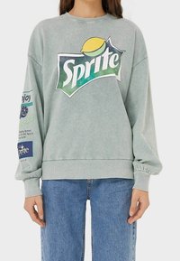 Miętowa bluza z dużym logo Sprite, z puffowanymi rękawami, ściągaczami i detalami tekstowymi na obu rękawach.