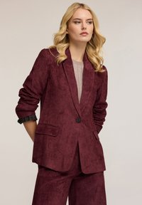 Blazer in corduroy bordeaux con una finitura leggermente texturizzata, caratterizzato da rever a punta, chiusura con un solo bottone e tasche frontali.