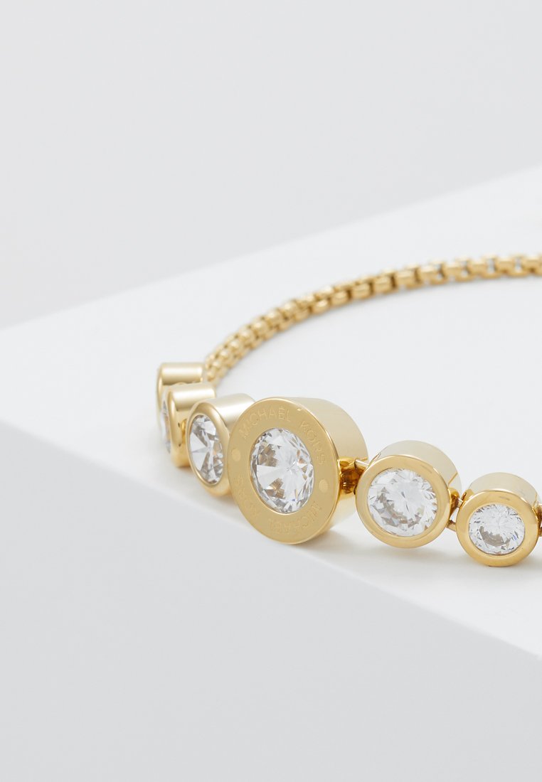 Goldarmband mit fünf kreisförmigen, klaren Steinen in aufsteigender Größe, eingefasst in glatten Goldfassungen mit einem strukturierten Gliederband.