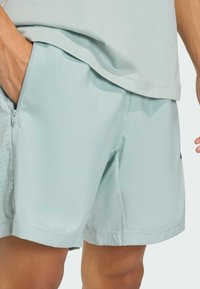 Pantalones cortos azul claro hechos de una tela suave y ligera. Presentan un bolsillo con cremallera en ángulo y detalles perforados sutiles en el lateral.