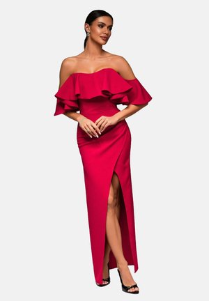 Abito rosso a spalle scoperte con maniche a ruches, design aderente, spacco alto fino alla coscia e texture liscia. Indossato con tacchi neri con cinturini.