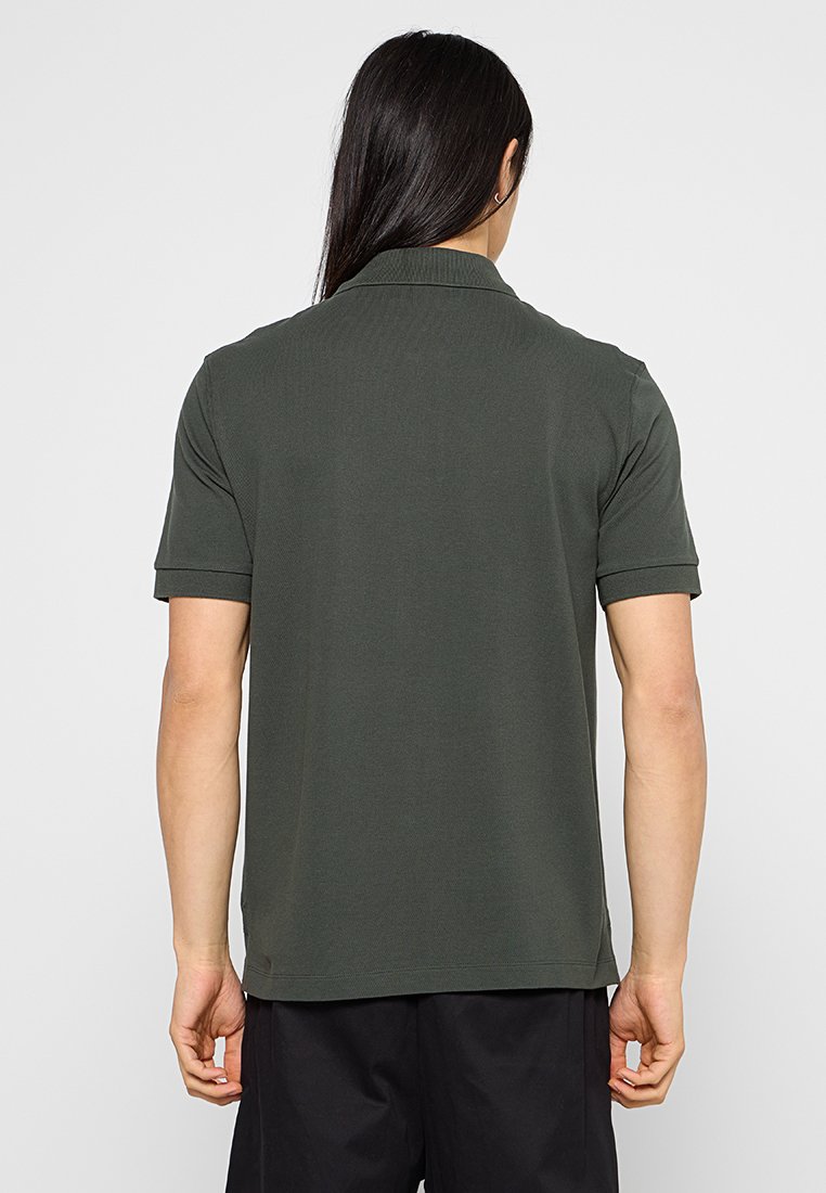 Dunkelgrünes Polohemd mit strukturiertem Strick, kurzen Ärmeln und umgeschlagenem Kragen. Glattes Material mit geradem Saum und ohne sichtbare Logos.