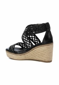 Sandalia de cuña tejida negra con un upper texturizado, punta al aire y tacón envuelto en yute. Presenta correas entrelazadas y una plantilla suave.