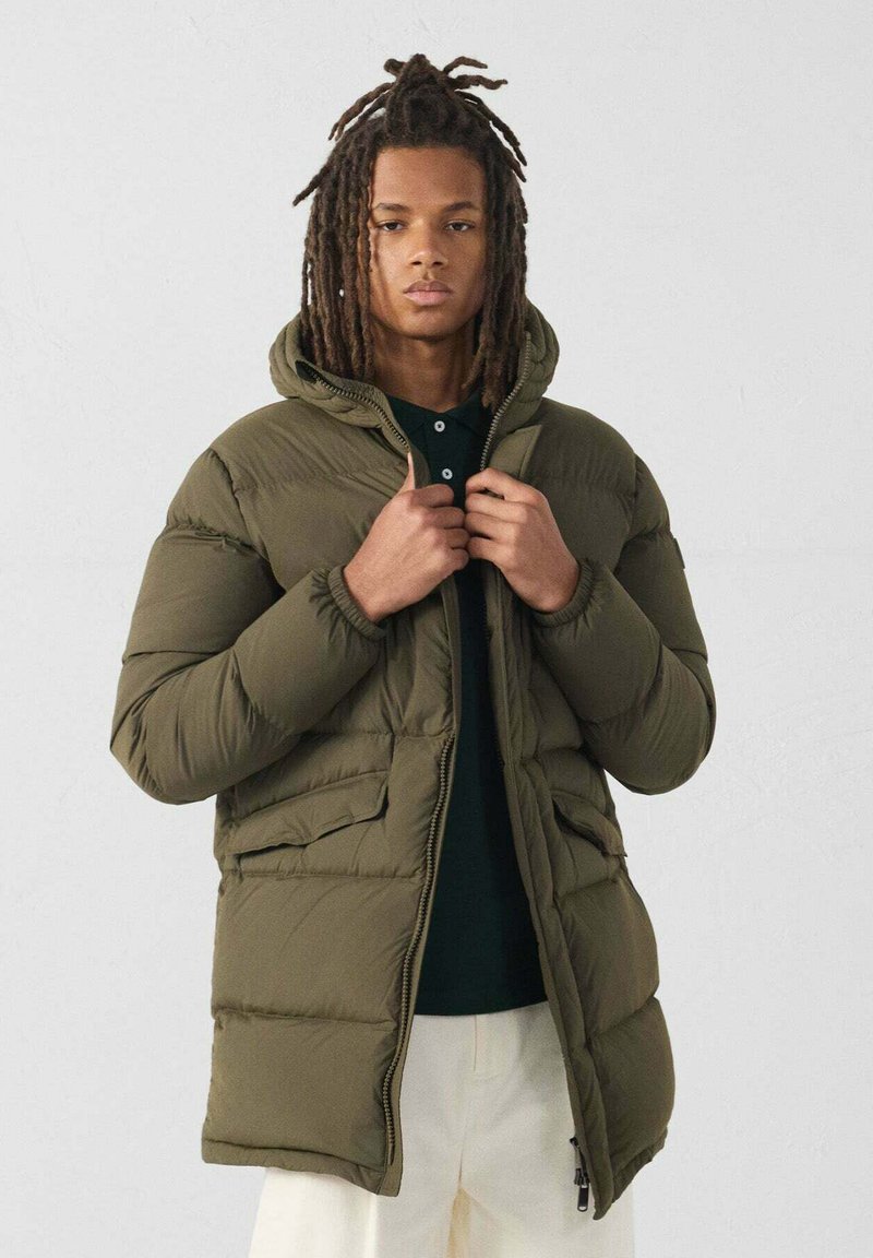 Olijfgroene pufferjack met capuchon, ritssluiting en twee voorkruiszakken. Heeft een gewatteerde structuur en elastische manchetten voor een betere pasvorm.