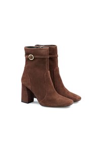 Stivaletti in suede marrone con tacco a blocco, punta affusolata e un dettaglio a fibbia circolare dorata su una cintura intorno alla caviglia.