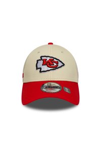 Beige baseball cap with a red brim. Features an embroidered Kansas City Chiefs logo in red and black. Adjustable fit.
